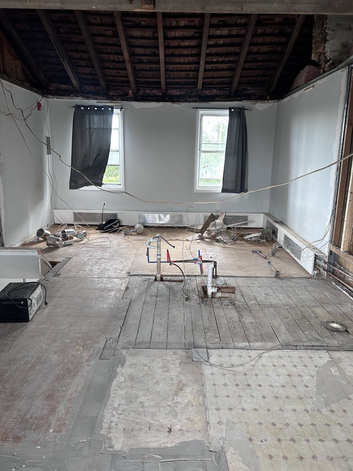 Residential interior gut demolition exposing roof framing and opened walls